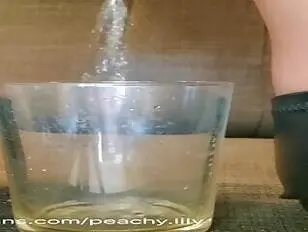 Peachy Lilly chaude en lingerie noire éjacule dans un verre puis fait pipi dans un autre